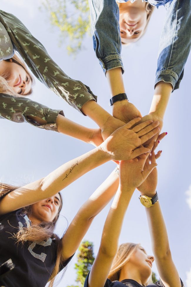 female-teen-friends-stacking-hands-together